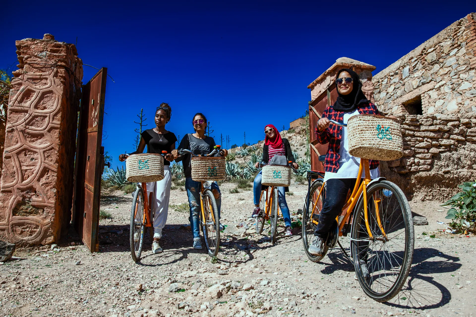 Women standing next to their bicycles amid Moroccan buildings